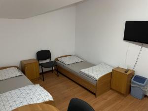 a room with two beds and a tv and a chair at Noclegi Pracownicze LAZUR in Ciechanów