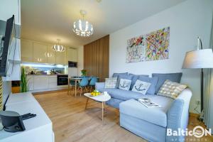 a living room with a blue couch and a kitchen at Apartamenty BalticON Polanki Park in Kołobrzeg