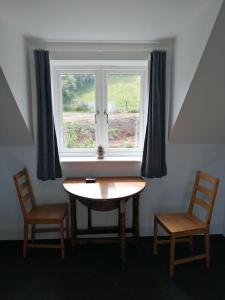 a table and two chairs in front of a window at Farm Loft in Shepton Mallet