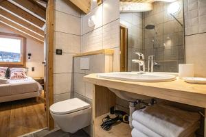 a bathroom with a sink and a toilet and a bed at Alpen Chalet in Morzine