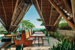 a restaurant with tables and chairs and a view of the ocean at Puro Surf Hotel & Performance Academy in El Zonte