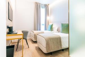 a hotel room with two beds and a desk and a mirror at Hotel Málaga Vibes in Málaga