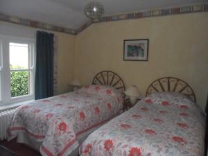 
two beds in a room with two windows at Stanshope Hall in Alstonfield

