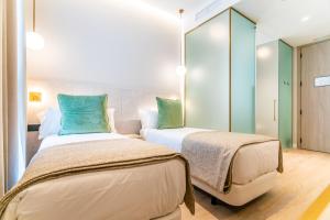 two beds in a room with green and blue pillows at Hotel Málaga Vibes in Málaga