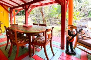 ein Kind steht auf einer Veranda mit einem Tisch und Stühlen in der Unterkunft VILLA La Perle PLAGE à PIED, PISCINE à Deshaies in Deshaies
