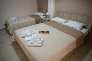 two beds in a hotel room with towels and glasses at Theo and Irin's Houses in Flogita