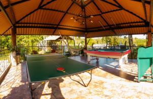 une terrasse avec des tables de ping-pong et un grand parasol dans l'établissement Hotel Campestre Nogal de Cafetal, à Quimbaya