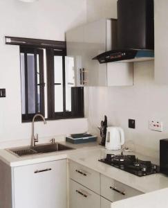 a white kitchen with a sink and a stove at Supreme Apartments in Ibadan