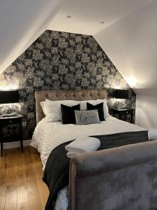 una camera da letto con un grande letto con carta da parati nera e grigia di Honeysuckle Cottage -PART OF ALTON COTTAGES ad Alton