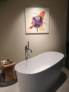 a bath tub in a bathroom with a painting on the wall at Maison et Florescence in Nuits-Saint-Georges