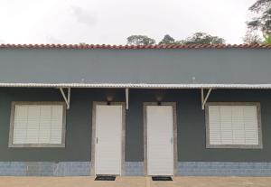 un edificio con cuatro puertas blancas. en Pousada Styllus Miguel Pereira en Miguel Pereira