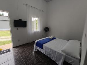 Habitación blanca con cama y TV en Pousada Styllus Miguel Pereira, en Miguel Pereira