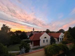a sunset over a house with a church in the background at Anna's Residency - Prestige Suite in Balatonkenese