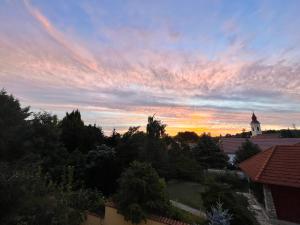 a sunset over a town with a church and a tower at Anna's Residency - Prestige Suite in Balatonkenese