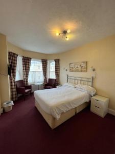 a bedroom with a bed and two chairs and a window at Haddon Hall Hotel in Eastbourne