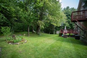 a yard with a tree and a deck at 14mi to Mt. Snow! Arcade, Private Suite, King Bed! in Whitingham +21 photos