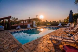 einen Pool mit Stühlen und Sonnenuntergang in der Unterkunft Alameda Galu in Atibaia