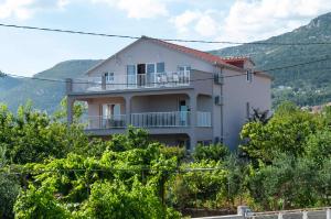 une maison blanche avec un balcon sur une colline dans l'établissement Apartment Sunshine, Sunrise, Sunset, à Kaštela