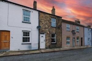 a row of houses on a street with a sunset at Charming Three Bedroom House near to Beach - Free WiFi and Breakfast in Kent