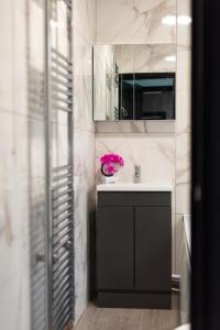 a bathroom with a sink and a vase of pink flowers at Charming Three Bedroom House near to Beach - Free WiFi and Breakfast in Kent