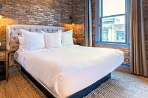 a large white bed in a room with a brick wall at Hip Urban Loft - Small Town Charm - 124 LOFTS #1 in West Dundee