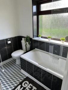 uma casa de banho com uma banheira, um WC e uma janela. em Charming 2-BR Property - Sleeps 5 em Warrington