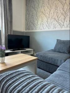 uma sala de estar com um sofá e uma televisão de ecrã plano em Charming 2-BR Property - Sleeps 5 em Warrington
