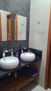 Baño con 2 lavabos en una encimera negra en SUÍTE EM PIPA COM CAFÉ DA MANHÃ, en Tibau do Sul