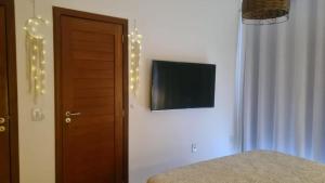 1 dormitorio con 1 cama y TV en la pared en SUÍTE EM PIPA COM CAFÉ DA MANHÃ, en Tibau do Sul