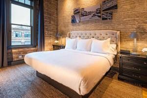 a bedroom with a large bed and a brick wall at Hip Urban Loft-Small Town Charm-124 LOFTS #2 in West Dundee