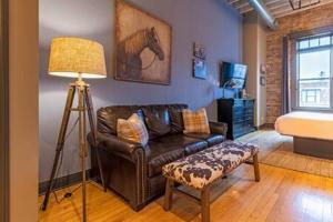 a living room with a leather couch and a lamp at Hip Urban Loft-Small Town Charm-124 LOFTS #2 in West Dundee