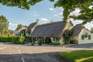 a house with a thatched roof on a street at The Green in Coneysthorpe