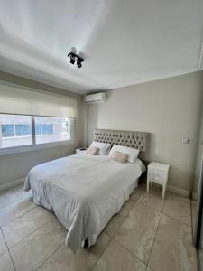 a white bedroom with a large bed and a window at Apart de categoría con amenities y estacionamiento in Buenos Aires