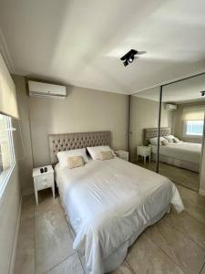 una camera da letto con un grande letto bianco e uno specchio di Apart de categoría con amenities y estacionamiento a Buenos Aires