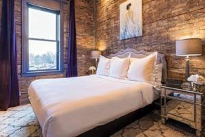 ein Schlafzimmer mit einem großen Bett und einer Ziegelwand in der Unterkunft Hip Urban Loft - Small Town Charm -124 LOFTS #3 in West Dundee