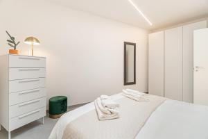biała sypialnia z łóżkiem i komodą w obiekcie Urban Garden by Blue Velvet Livings w Mediolanie