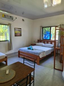 a bedroom with a bed and a table and windows at Casapreciosa-LasLajas in Las Lajas