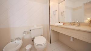 a white bathroom with a toilet and a sink at Bagu Villa de Mar in Punta del Este