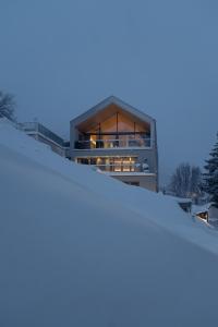 Una casa en la nieve al anochecer en Omaela Apartments, en Sankt Anton am Arlberg