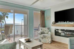 a living room with a flat screen tv and a living room with a balcony at Oceans Pointe Nantucket inspired condo on the bay in Tampa