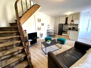 uma sala de estar com uma escada, um sofá e uma mesa em Appartement 2chambres/PuyDuFou em Mauléon