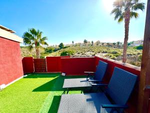 einen Balkon mit 2 Stühlen, einem Tisch und Palmen in der Unterkunft 4 Estudio-Solárium Gran Alacant in Puerto Marino