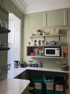 uma cozinha com paredes verdes e um micro-ondas no balcão em Bath Backpackers em Bath