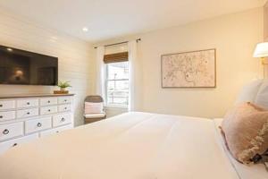 a white bedroom with a large bed and a television at Downtown Luxury Farmhouse Apartment #1 in West Dundee