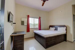 a bedroom with a bed and a window with red curtains at SPOT ON San Tower Hotel in Kilimanūr