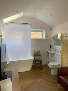 a bathroom with a tub and a toilet and a sink at The chalet in Chandlers Ford