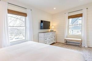 a white bedroom with a bed and two windows at Downtown Luxury Farmhouse Apartment #3 in West Dundee