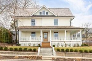 uma casa branca com um alpendre branco e escadas em Downtown Luxury Farmhouse Apartment #4 em West Dundee