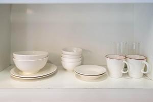 a shelf with bowls and cups and plates on it at We Home Ben Thanh in Ho Chi Minh City