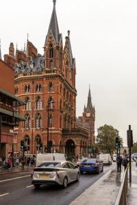 a street with cars parked in front of a large building at Kabannas London St Pancras in London
